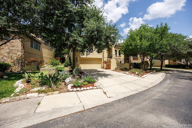 view of property hidden behind natural elements featuring concrete driveway, stucco siding, and a garage