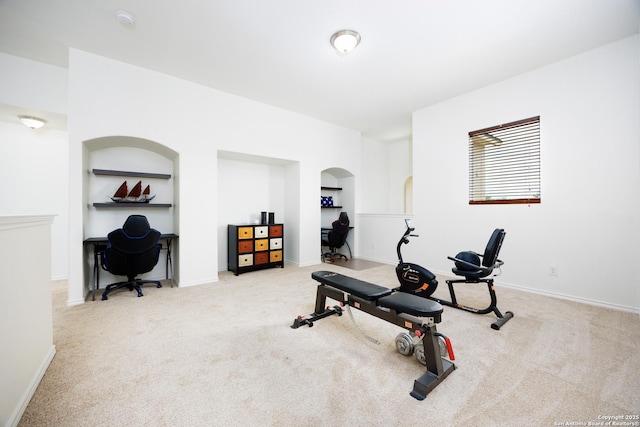 exercise room with carpet floors, arched walkways, and baseboards