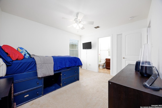 bedroom with light carpet, connected bathroom, and a ceiling fan