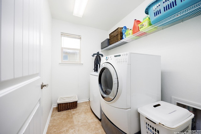 clothes washing area featuring washing machine and dryer and baseboards