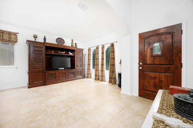 foyer entrance with arched walkways, light tile patterned flooring, and baseboards