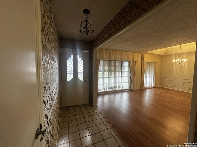 entryway with a chandelier, tile patterned flooring, and a textured ceiling