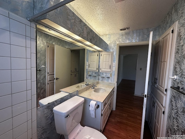 bathroom featuring wallpapered walls, wood finished floors, toilet, a textured ceiling, and vanity