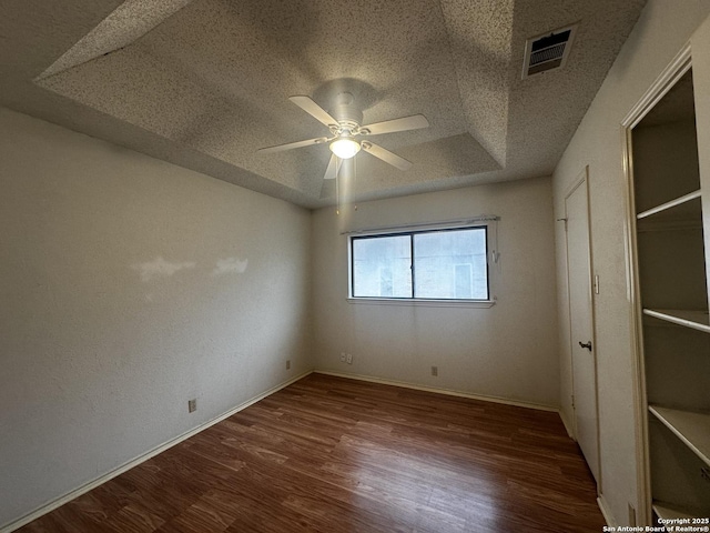 unfurnished bedroom featuring a textured ceiling, wood finished floors, baseboards, and a ceiling fan