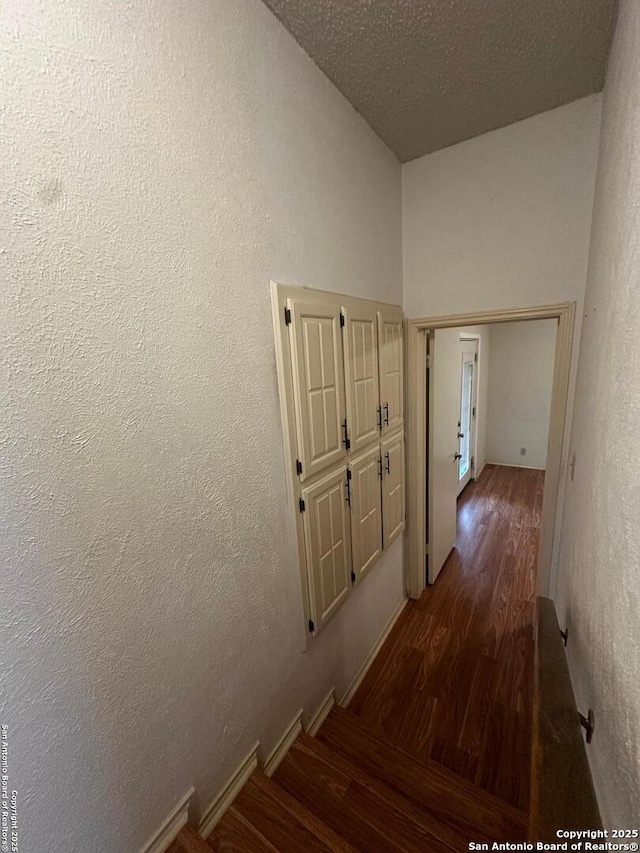 hallway featuring wood finished floors and a textured wall