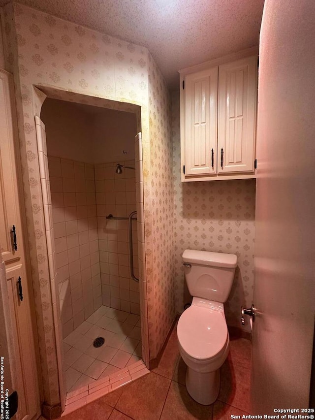 bathroom featuring a shower stall, toilet, tile patterned flooring, wallpapered walls, and a textured ceiling