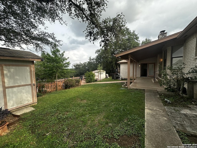 view of yard with a shed, a patio, and an outdoor structure