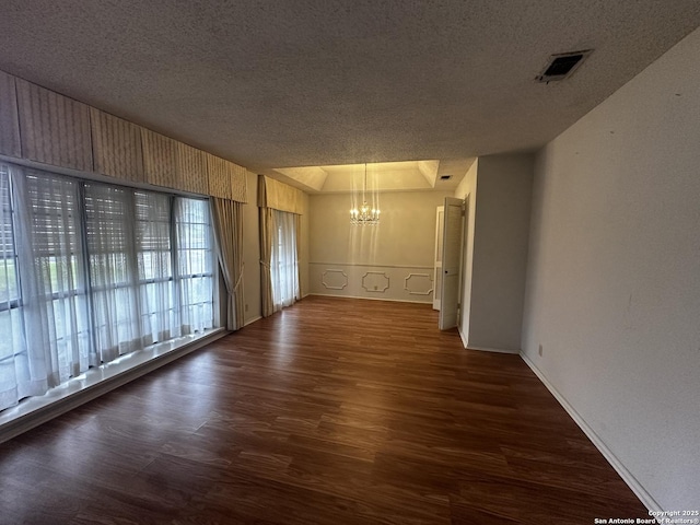 spare room with a chandelier, dark wood-style flooring, a textured ceiling, and baseboards