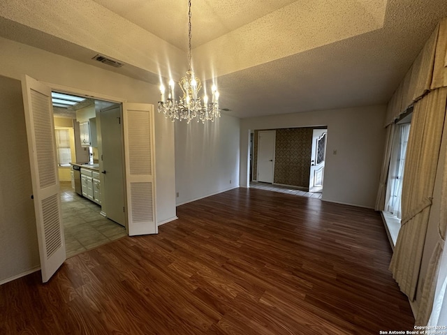 unfurnished dining area with a chandelier, dark wood-type flooring, baseboards, and a textured ceiling