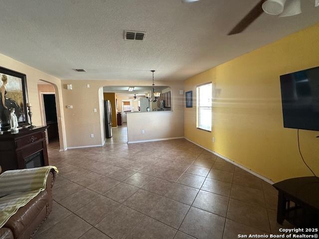 351 Fontana Albero, San Antonio, TX 78253 - unfurnished living room featuring arched walkways, a ceiling fan, dark tile patterned flooring, baseboards, and a textured ceiling