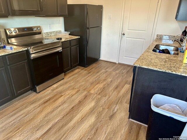 11719 Claudette St, San Antonio, TX 78252 - kitchen featuring black appliances, light wood-style flooring, a sink, and light stone counters