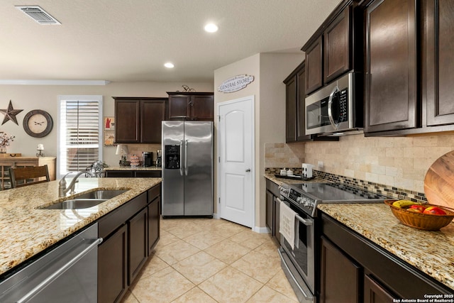 929 Cypress Ml, New Braunfels, TX 78130 - kitchen with stainless steel appliances, a sink, decorative backsplash, light tile patterned flooring, and light stone counters