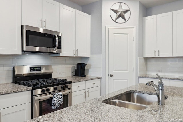 8911 Rancher Pl, Seguin, TX 78155 - kitchen with appliances with stainless steel finishes, a sink, white cabinetry, and backsplash
