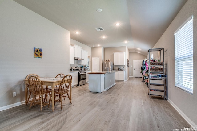 13627 Crossbow, San Antonio, TX 78253 - kitchen featuring stainless steel appliances, light wood-type flooring, an island with sink, white cabinets, and vaulted ceiling