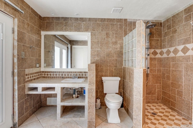 bathroom featuring tiled shower, tile walls, tile patterned floors, toilet, and vanity