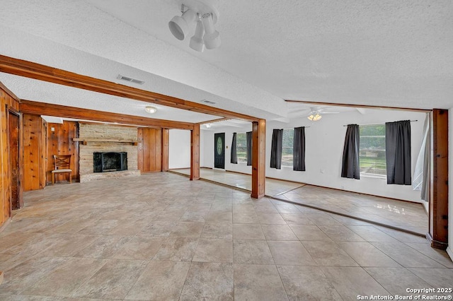 235 Altgelt, San Antonio, TX 78201 - unfurnished living room with a textured ceiling, healthy amount of natural light, a brick fireplace, wood walls, and baseboards