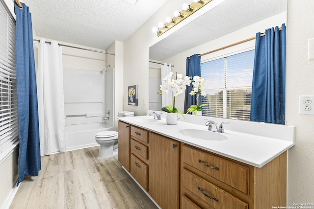 9206 Dancove Dr, San Antonio, TX 78250 - full bath with wood finished floors, toilet, shower / tub combo, a textured ceiling, and double vanity