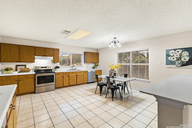 9206 Dancove Dr, San Antonio, TX 78250 - kitchen featuring appliances with stainless steel finishes, a sink, under cabinet range hood, light countertops, and brown cabinets