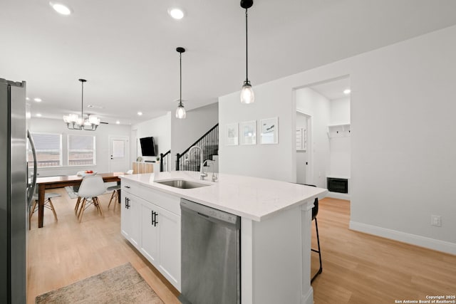 kitchen with stainless steel appliances, a sink, white cabinets, light wood-style floors, and recessed lighting