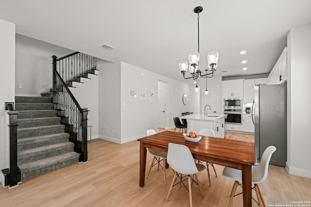 dining room featuring stairway, light wood-style flooring, a chandelier, baseboards, and recessed lighting
