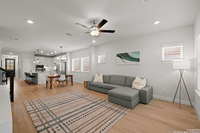 living room featuring baseboards, light wood finished floors, plenty of natural light, a ceiling fan, and recessed lighting