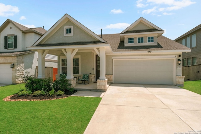 view of front facade with a porch, a front yard, driveway, stone siding, and a shingled roof