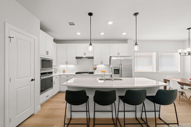 kitchen with appliances with stainless steel finishes, light countertops, backsplash, a breakfast bar area, and recessed lighting