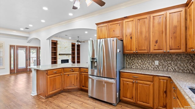 24935 Pecan Crk, San Antonio, TX 78255 - kitchen with stainless steel fridge with ice dispenser, ceiling fan, ornamental molding, a peninsula, and a fireplace