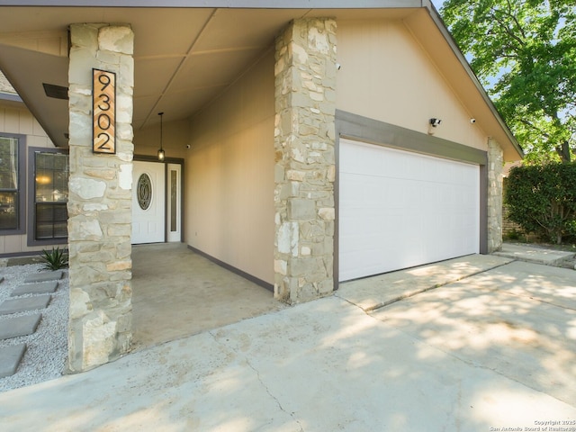 entrance to property with concrete driveway and stone siding