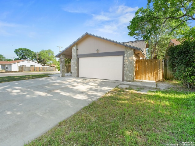 view of front facade with driveway, a garage, fence, and stone siding