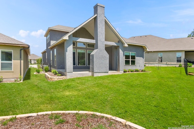 rear view of house with stucco siding, a yard, and a chimney