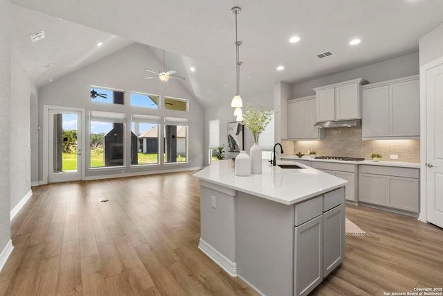 kitchen with open floor plan, a sink, ceiling fan, light wood-type flooring, and light countertops