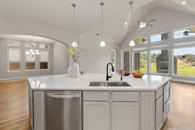 kitchen featuring appliances with stainless steel finishes, a sink, a kitchen island with sink, light wood-style floors, and light countertops