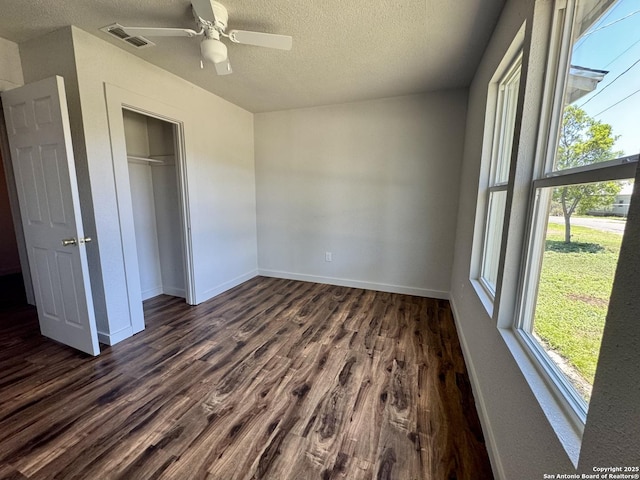 419 W Culberson, Sabinal, TX 78881 - unfurnished bedroom featuring a textured ceiling, dark wood-style flooring, a closet, baseboards, and a ceiling fan