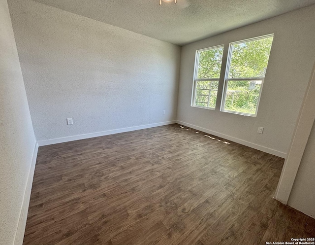 419 W Culberson, Sabinal, TX 78881 - spare room featuring dark wood-type flooring, a textured ceiling, baseboards, and a textured wall