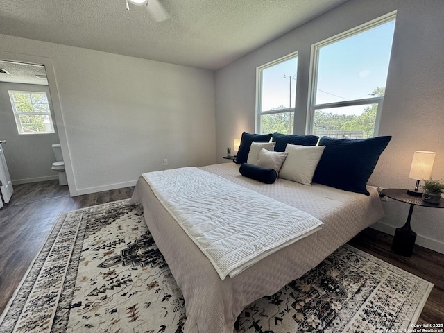 419 W Culberson, Sabinal, TX 78881 - bedroom with dark wood-type flooring, baseboards, a textured ceiling, and ensuite bath