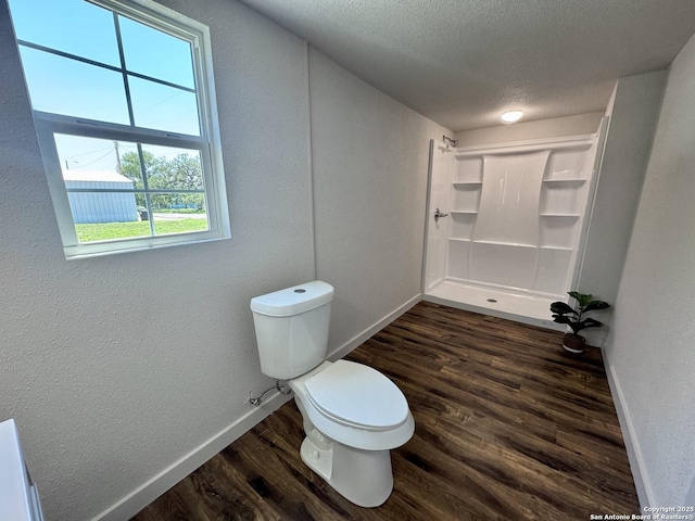 419 W Culberson, Sabinal, TX 78881 - bathroom featuring wood finished floors, baseboards, toilet, a textured ceiling, and a textured wall