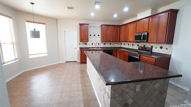 kitchen with appliances with stainless steel finishes, tasteful backsplash, a kitchen island, a sink, and baseboards