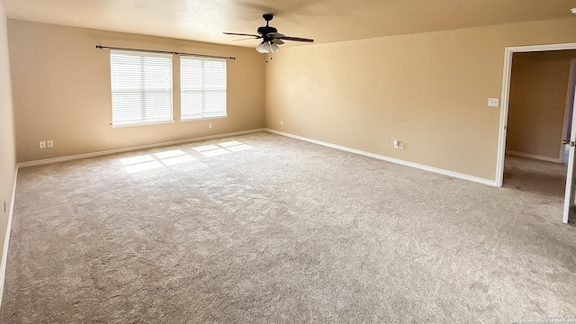 spare room featuring a ceiling fan, carpet, and baseboards