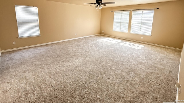 carpeted spare room featuring ceiling fan and baseboards