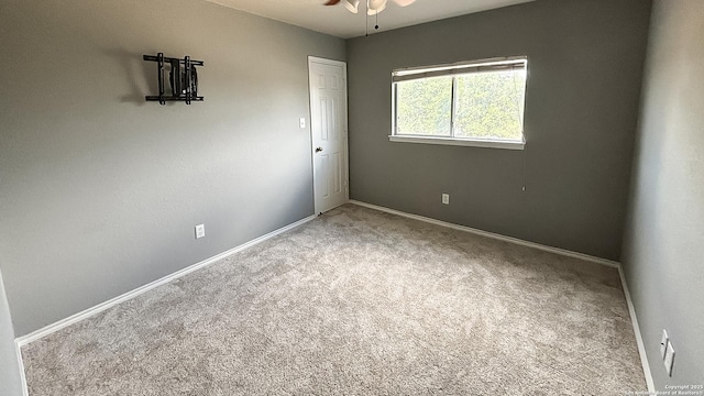 carpeted spare room with a ceiling fan and baseboards