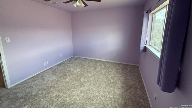 carpeted empty room featuring ceiling fan and baseboards