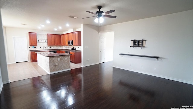 kitchen with stainless steel appliances, ceiling fan, arched walkways, wood finished floors, and a sink