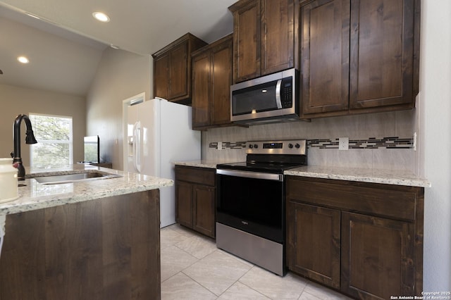 1407 Tanglewood, Spring Branch, TX 78070 - kitchen featuring stainless steel appliances, a sink, decorative backsplash, vaulted ceiling, and dark brown cabinetry