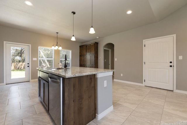 1407 Tanglewood, Spring Branch, TX 78070 - kitchen with arched walkways, a sink, dark brown cabinets, an island with sink, and light stone countertops