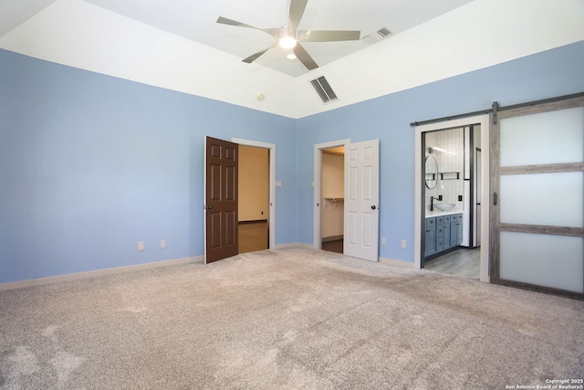 1181 County Road 4516, Castroville, TX 78009 - unfurnished bedroom with carpet flooring, a barn door, a spacious closet, baseboards, and ensuite bathroom