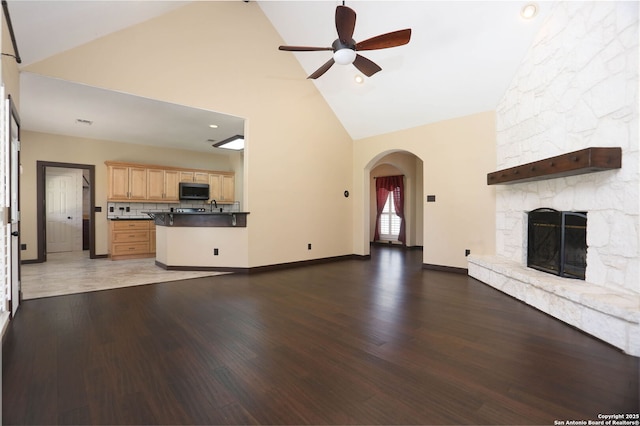 1181 County Road 4516, Castroville, TX 78009 - unfurnished living room featuring high vaulted ceiling, ceiling fan, a fireplace, arched walkways, and a sink