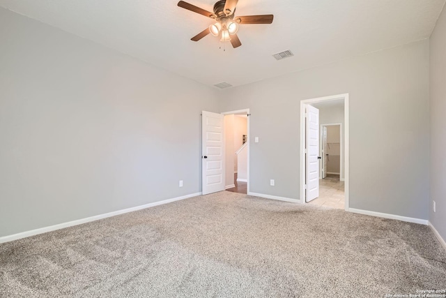 unfurnished bedroom with light colored carpet, a spacious closet, baseboards, and ceiling fan