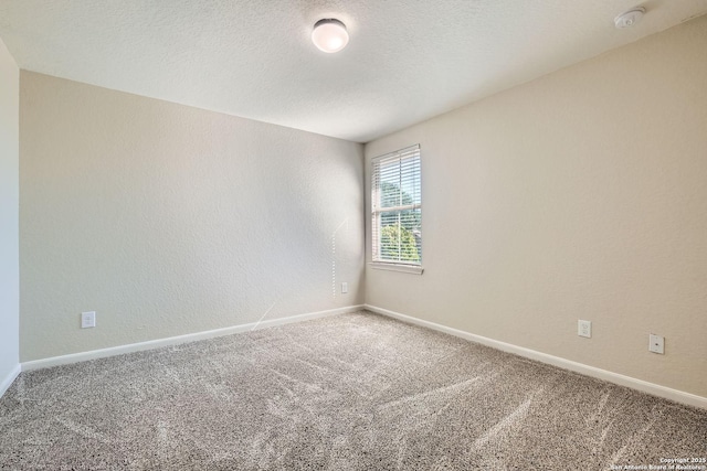 carpeted spare room featuring baseboards and a smoke detector