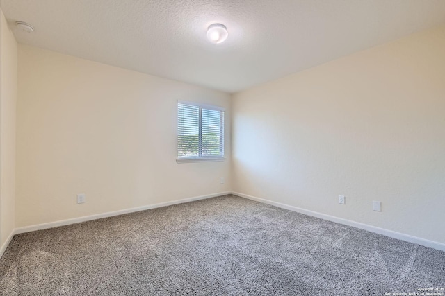 empty room with carpet flooring, baseboards, and a smoke detector